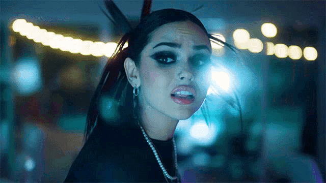 a close up of a woman 's face in a dark room with lights behind her
