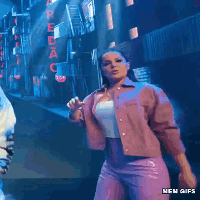 a woman in a pink jacket and purple pants is dancing on a stage with a stop sign in the background .