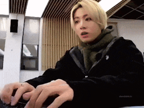 a young man with blonde hair is typing on a laptop computer .