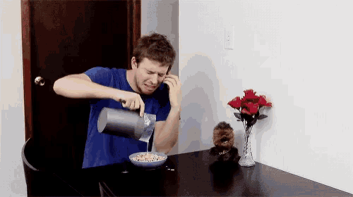 a man is pouring cereal into a bowl and talking on a cell phone