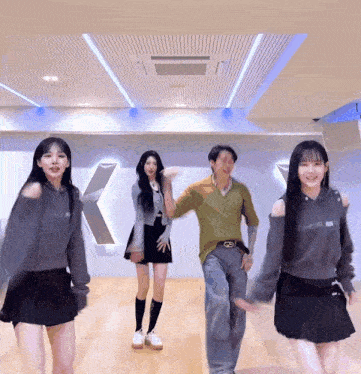 a man and two women are dancing in a room with a sign that says k