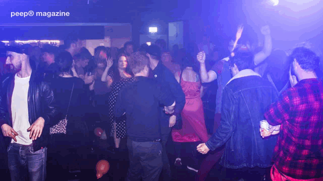 a crowd of people are dancing in a dark room with the words peep magazine visible