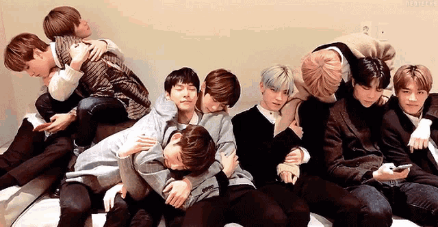 a group of young men are hugging each other while sitting on a bed .