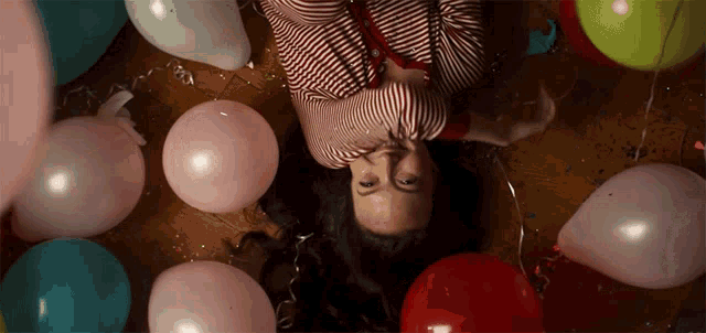 a woman laying on the floor with balloons around her
