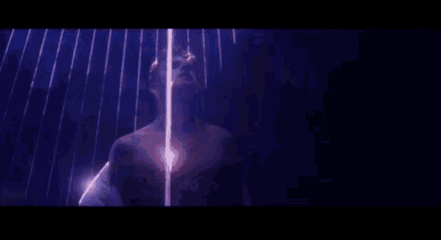 a man without a shirt is laying in a dark room surrounded by lights .