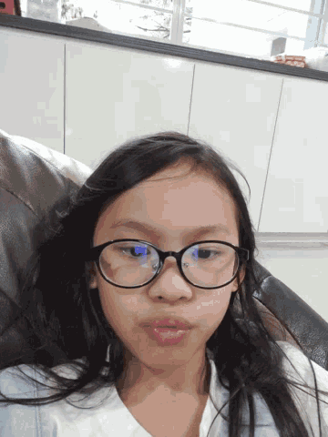 a young girl wearing glasses is laying on a chair