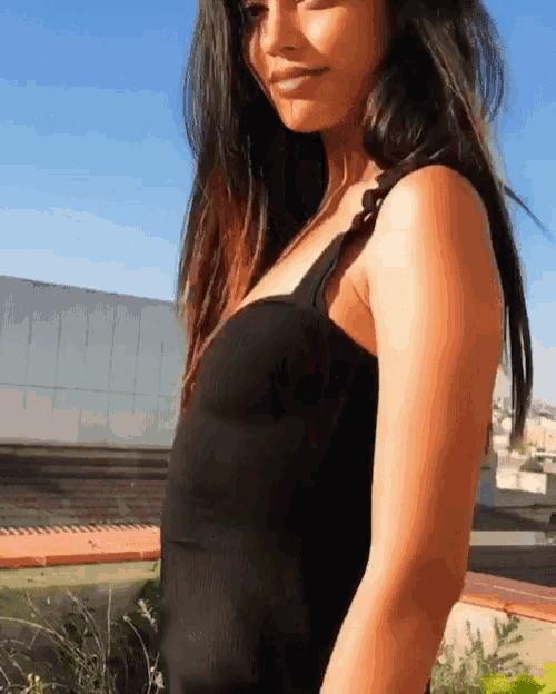 a woman in a black dress is standing on a balcony