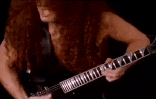 a man with long hair is playing a guitar on stage .