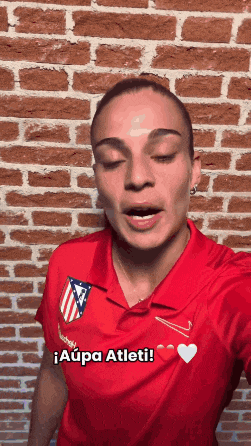 a woman wearing a red shirt that says aupa atleti on it