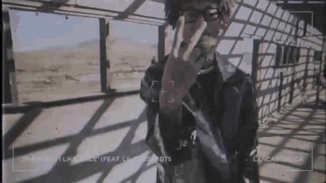 a man in a leather jacket is giving the middle finger while standing in front of a building .