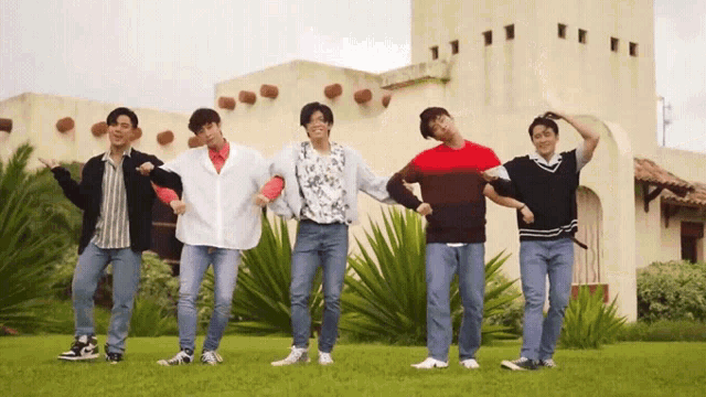 a group of young men are standing in front of a building