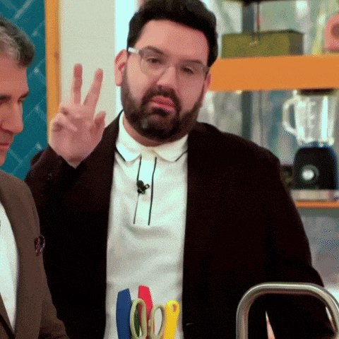 a man with a beard and glasses is giving the peace sign