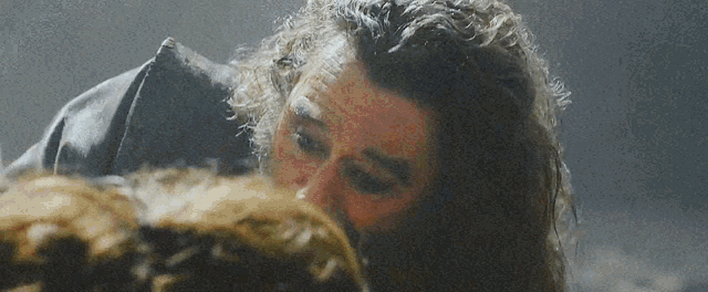 a man with curly hair is kissing a woman 's forehead .