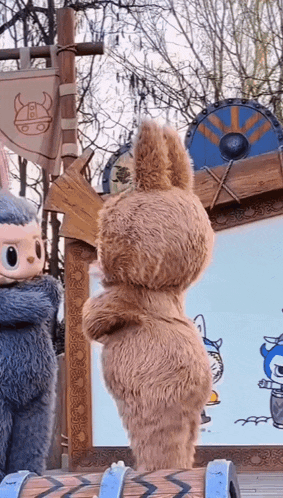 two stuffed animals are standing next to each other in front of a sign with a viking head on it