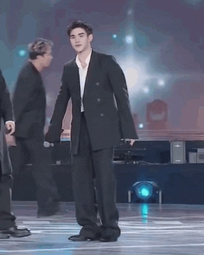 a man in a suit is standing on a stage with a microphone .