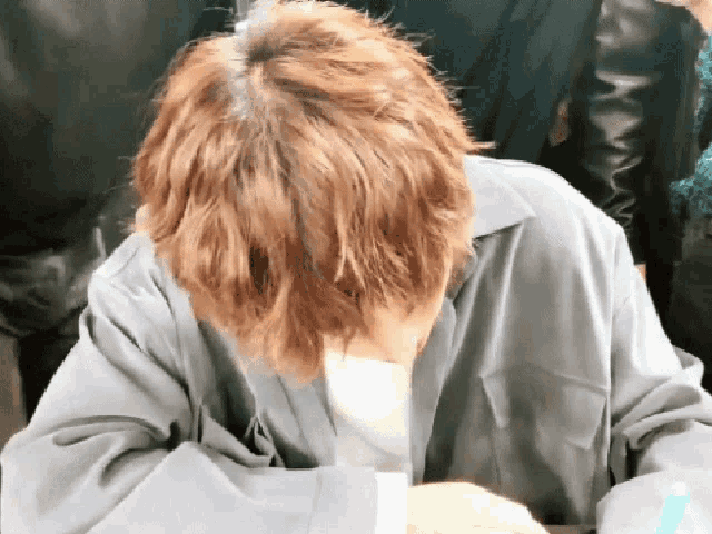 a person with red hair is covering their face with their hands