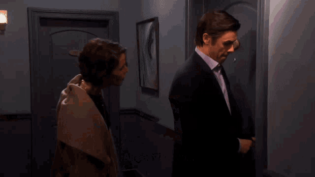 a man and a woman are standing in front of a door that has a sign that says exit