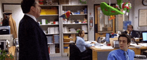 a man in a suit and tie is standing in an office talking to another man