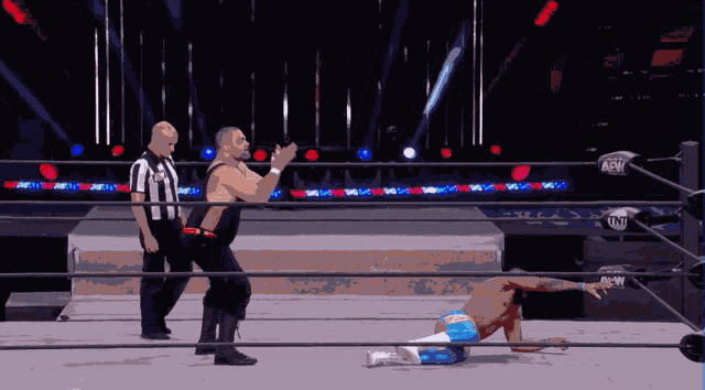 a wrestler is laying on the ground in a wrestling ring with a referee