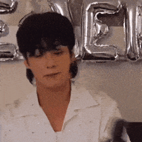a man in a white shirt is standing in front of balloons that spell out the word ' e ' .