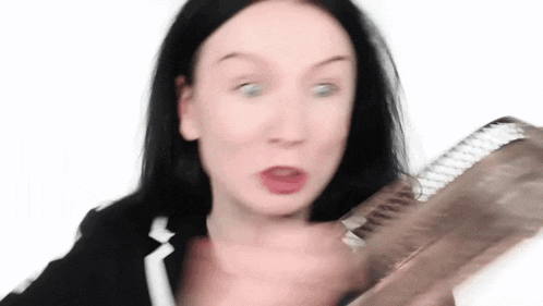 a woman is holding a piece of paper in her hand and making a face .