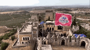 an aerial view of a castle with a redbull wololo flag flying in the air
