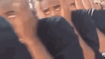 a man without a shirt is covering his face with his hands in a blurry picture .