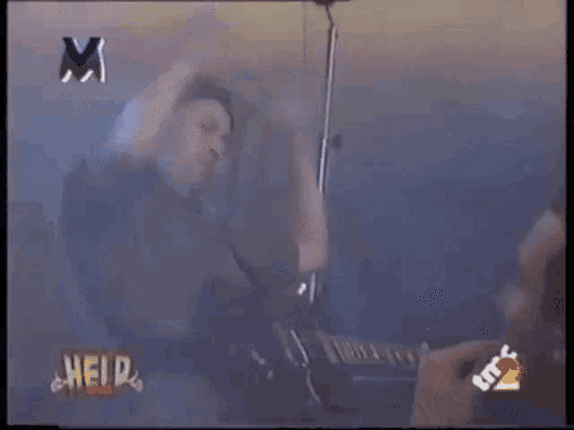 a man playing a guitar in front of a heid logo