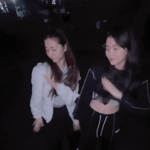 a couple of women standing next to each other in the dark