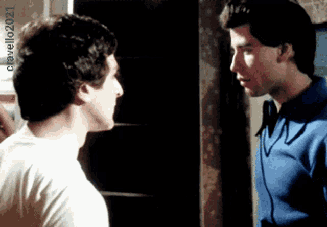 two men are standing next to each other and one of them is wearing a blue shirt and the other is wearing a white shirt