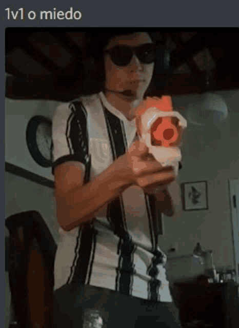 a man wearing headphones and sunglasses is holding a nerf gun in his hand