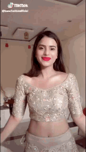 a woman wearing a crop top and a skirt is standing in a room .