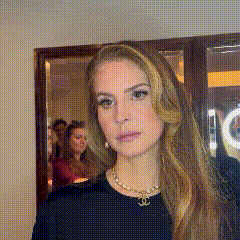 a woman wearing a black shirt and a necklace with a chanel logo on it