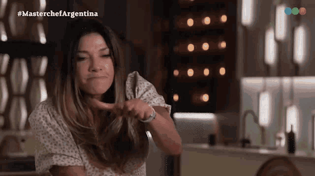 a woman is making a funny face in front of a sign that says masterchefargentina