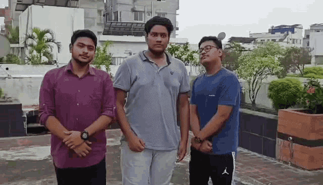 three young men are posing for a picture on a rooftop .