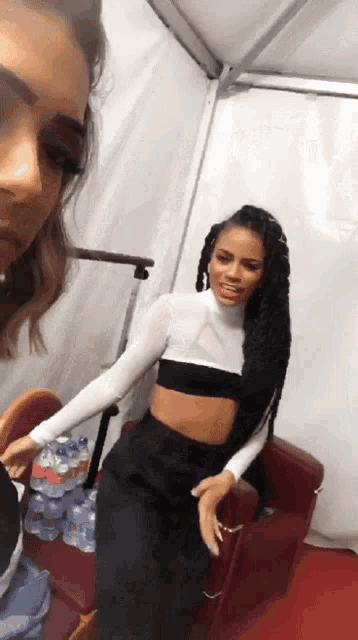 two women are standing next to each other in a room with bottles of water in the background