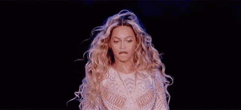 a woman with long blonde hair is making a funny face while standing on a stage .
