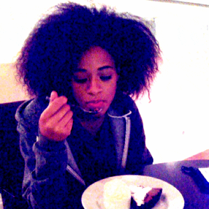 a woman is eating a piece of cake with a spoon