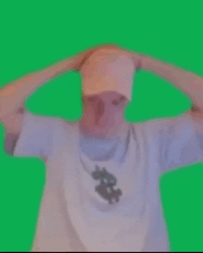a man in a white shirt is standing in front of a green screen and making a funny face .