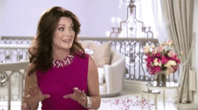 a woman in a pink dress and necklace is standing in a living room .