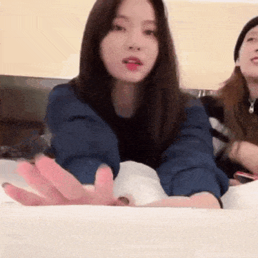 a woman in a blue jacket is laying on a bed with her hands outstretched .