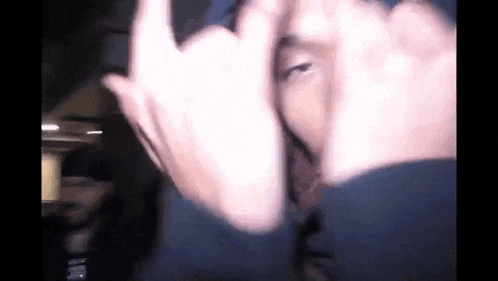 a man is making a peace sign with his hands while wearing a blue hat .
