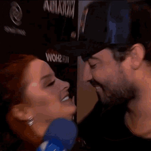 a man and a woman are kissing in front of a sign that says wohl