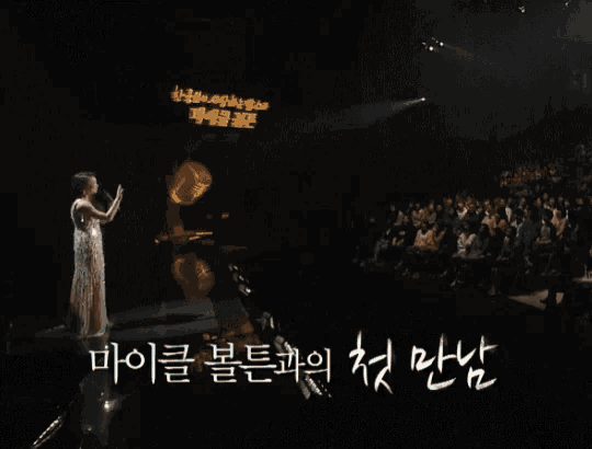 a woman singing into a microphone with korean writing on the bottom right
