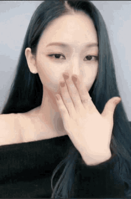 a woman with long black hair is blowing a kiss with her hand