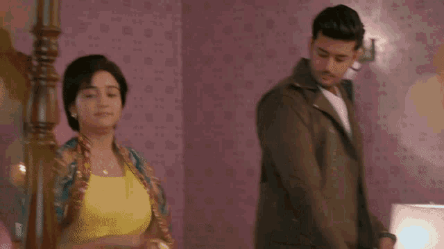 a man in a leather jacket is standing in a room with pink wallpaper