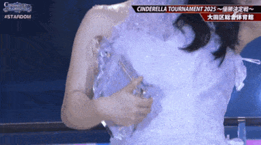 a woman in a white dress is holding a trophy in front of a sign that says cinderella tournament