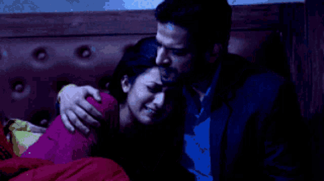 a man in a suit is hugging a woman in a bed