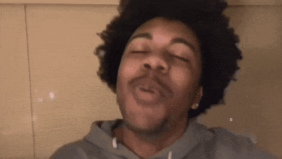 a man with curly hair is making a funny face with his eyes closed and his mouth open .