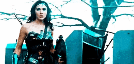 a woman in a wonder woman costume is standing in front of a tree holding a sword .
